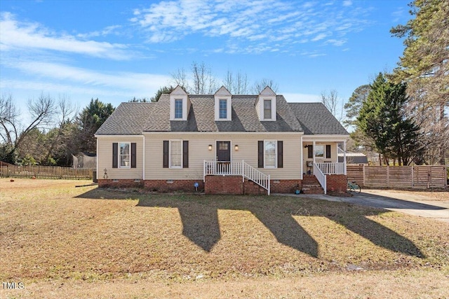 cape cod-style house with roof with shingles, crawl space, covered porch, fence, and a front yard