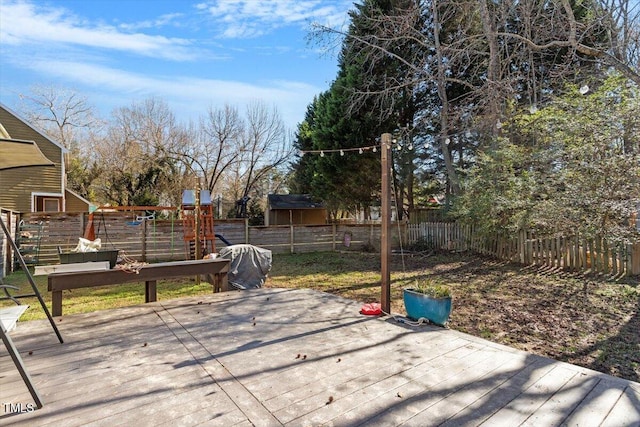 view of patio with a deck, a playground, and a fenced backyard