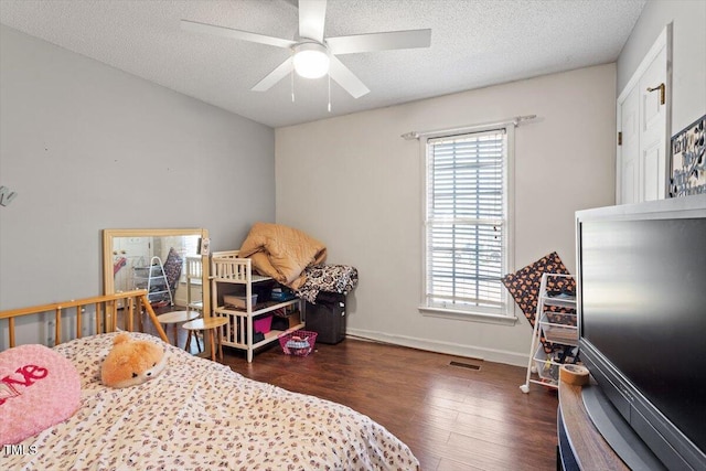 bedroom with dark wood-style flooring, multiple windows, a textured ceiling, and baseboards