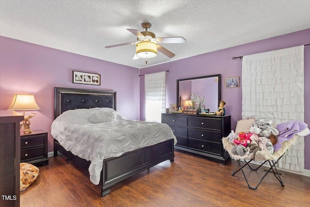 bedroom with ceiling fan, dark wood finished floors, and a textured ceiling