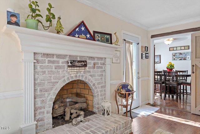 details with ornamental molding, a brick fireplace, and wood finished floors