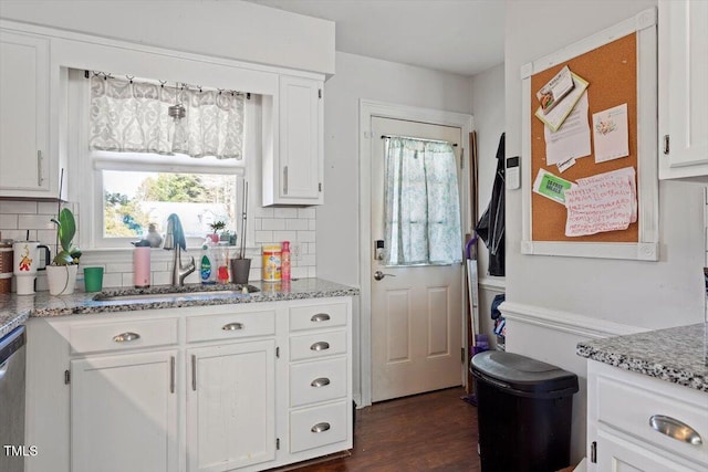 kitchen featuring white cabinetry, a sink, decorative backsplash, and light stone countertops