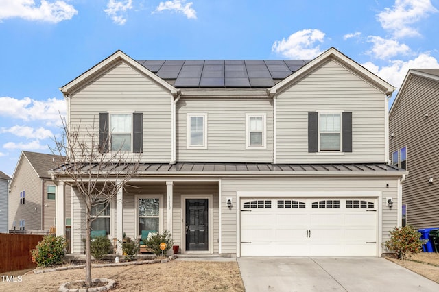 view of front facade with metal roof, a garage, solar panels, driveway, and a standing seam roof