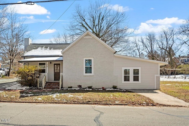 view of front of house with covered porch, a chimney, and brick siding