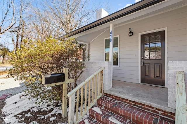 snow covered property entrance featuring a porch