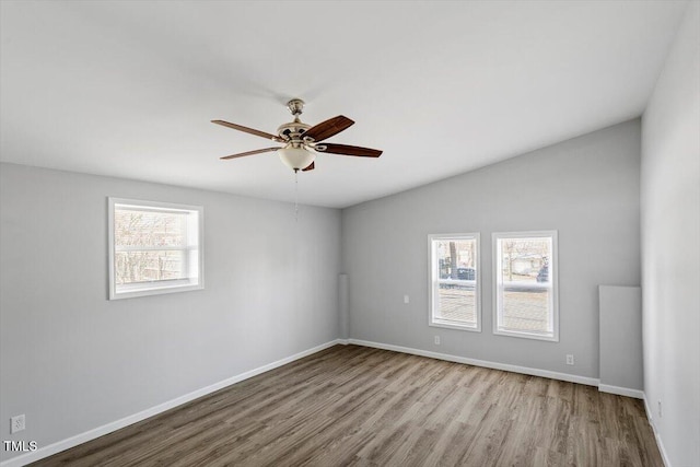 empty room with light wood-type flooring, ceiling fan, baseboards, and vaulted ceiling