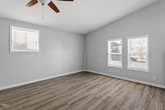 spare room with light wood-style floors, vaulted ceiling, baseboards, and ceiling fan