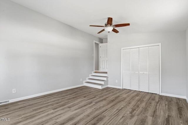 unfurnished bedroom with a closet, wood finished floors, visible vents, and baseboards