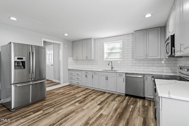 kitchen with dark wood-style floors, gray cabinets, stainless steel appliances, and a sink