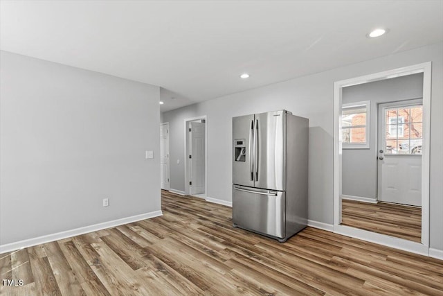 kitchen with baseboards, recessed lighting, wood finished floors, and stainless steel fridge with ice dispenser