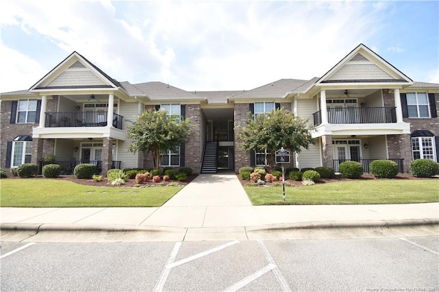 view of property featuring a balcony, a front lawn, and brick siding