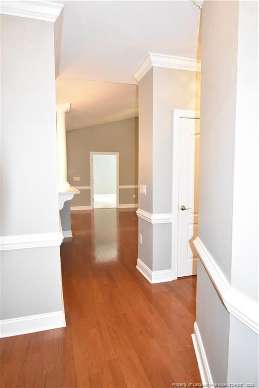 corridor featuring lofted ceiling, ornamental molding, dark wood finished floors, and baseboards