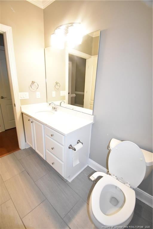 bathroom with toilet, wood tiled floor, vanity, and baseboards