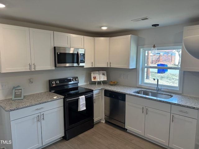 kitchen with stainless steel appliances, a sink, and white cabinets