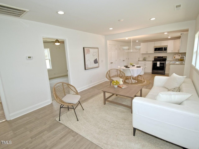 living room with light wood-type flooring, visible vents, and recessed lighting