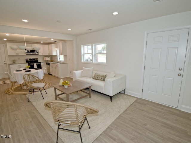 living area featuring baseboards, light wood-type flooring, and recessed lighting