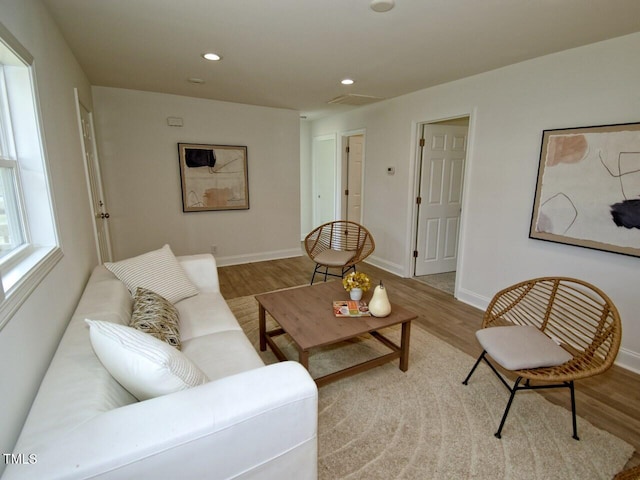 living area with baseboards, wood finished floors, and recessed lighting