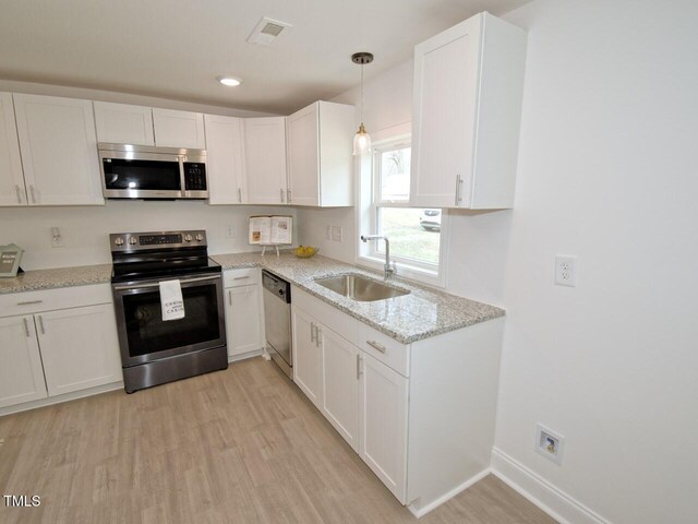 kitchen featuring appliances with stainless steel finishes, a sink, visible vents, and white cabinetry