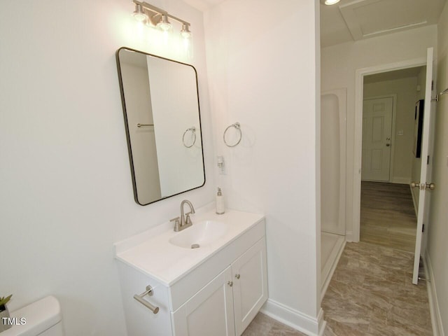 bathroom featuring toilet, walk in shower, vanity, and baseboards