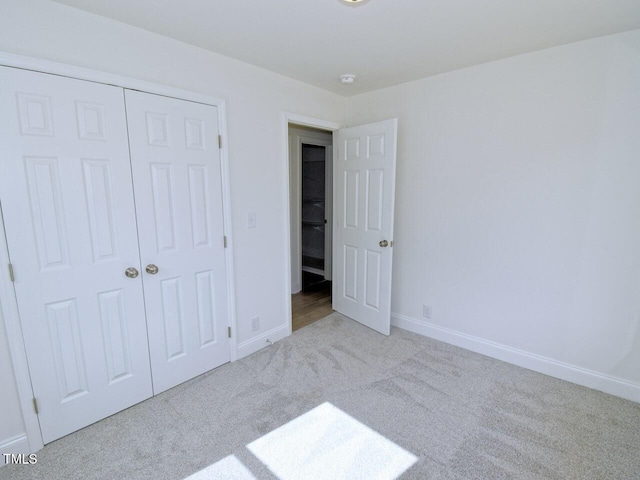 unfurnished bedroom featuring carpet, baseboards, and a closet