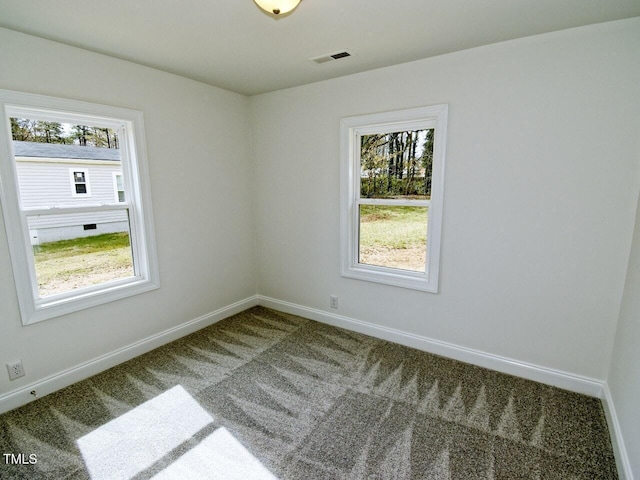 spare room with carpet floors, plenty of natural light, visible vents, and baseboards