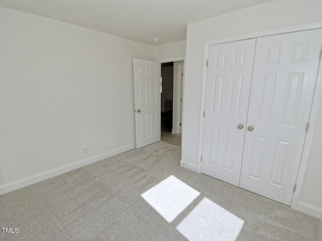 unfurnished bedroom with baseboards, a closet, and light colored carpet