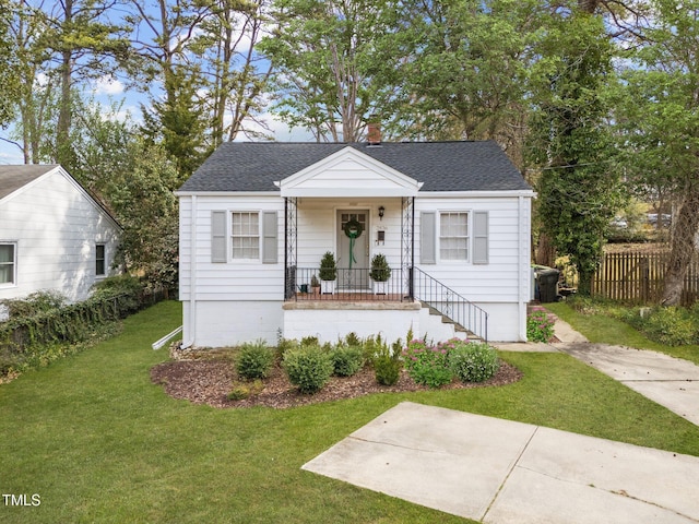 bungalow-style home featuring a shingled roof, a front yard, and fence