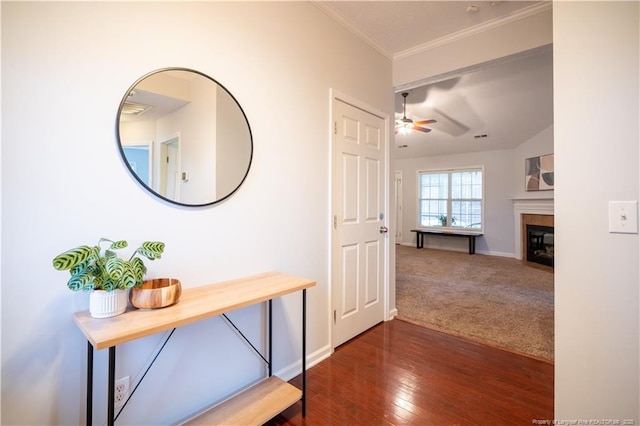 corridor with dark wood-style floors, dark colored carpet, baseboards, and crown molding