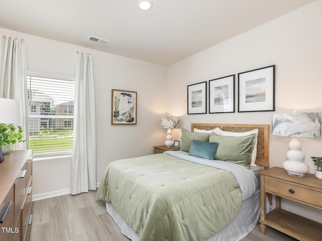 bedroom featuring light wood-style flooring, visible vents, and baseboards