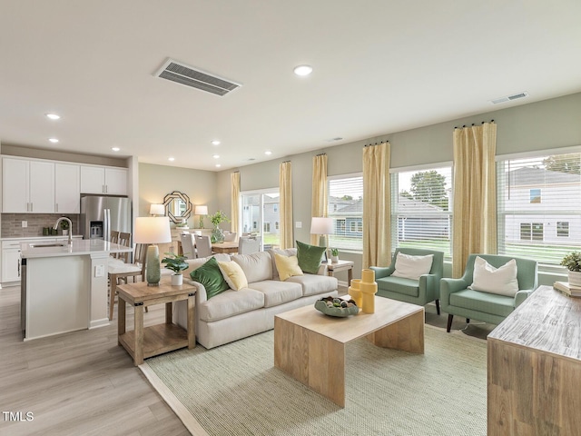 living room featuring light wood-style flooring, visible vents, and recessed lighting