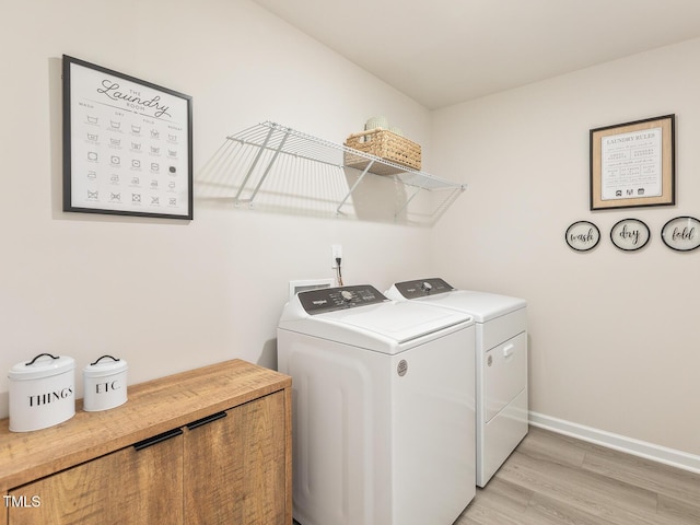 laundry room featuring laundry area, baseboards, light wood finished floors, and washing machine and clothes dryer