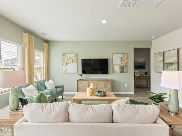 living area featuring visible vents, baseboards, and wood finished floors