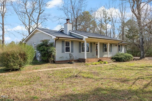 ranch-style home featuring a porch, a chimney, and a front yard