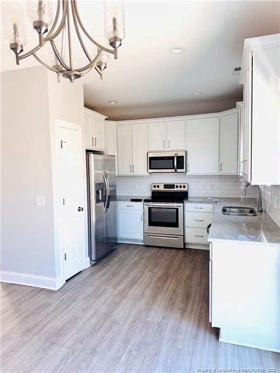 kitchen featuring stainless steel appliances, white cabinetry, a sink, and decorative backsplash