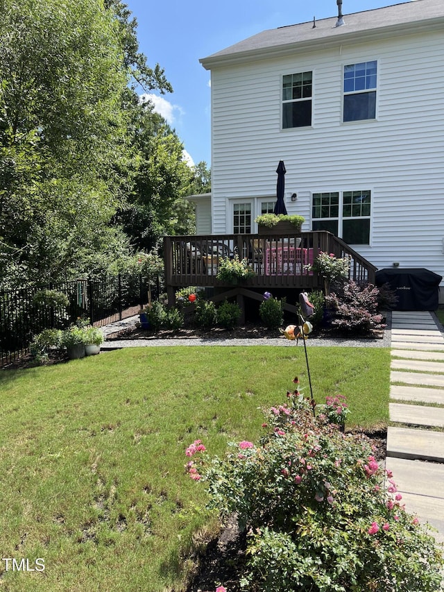 rear view of house with fence, a deck, and a yard