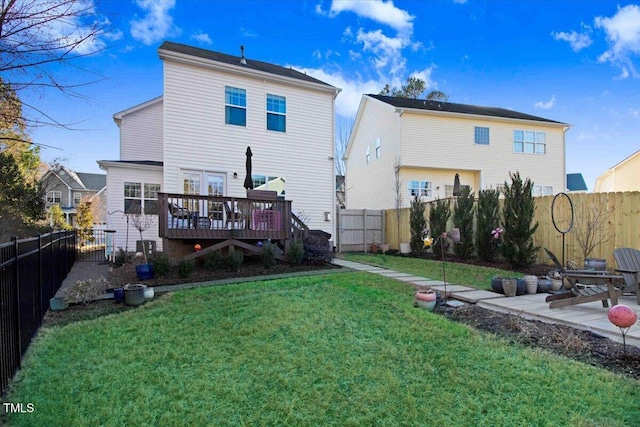 rear view of house with a deck, a patio, a lawn, and a fenced backyard