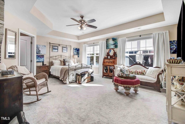 carpeted bedroom featuring a ceiling fan and a tray ceiling