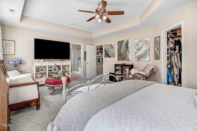 bedroom featuring carpet, visible vents, a tray ceiling, and a spacious closet