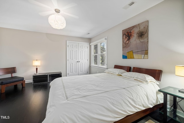 bedroom featuring a closet, dark wood finished floors, visible vents, and baseboards