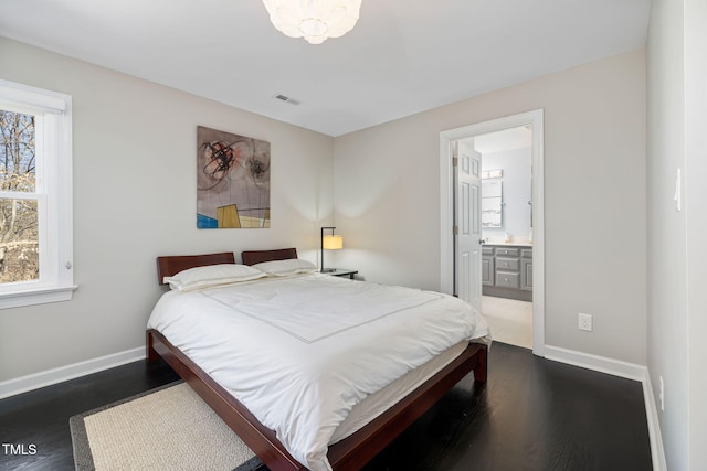 bedroom with dark wood-style flooring, visible vents, connected bathroom, and baseboards