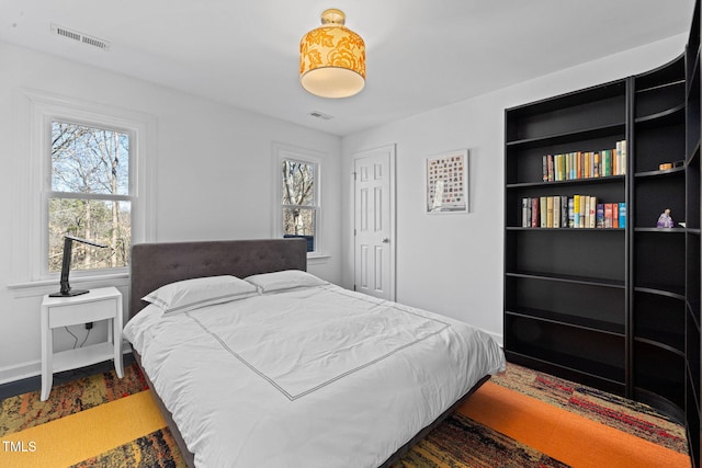 bedroom with visible vents, dark wood finished floors, and baseboards