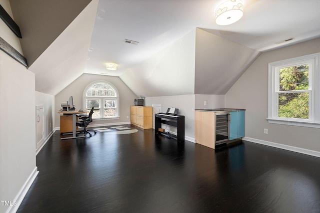 office featuring vaulted ceiling, visible vents, and dark wood finished floors