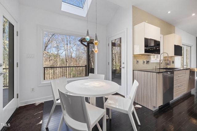 dining room with lofted ceiling with skylight, dark wood finished floors, and plenty of natural light