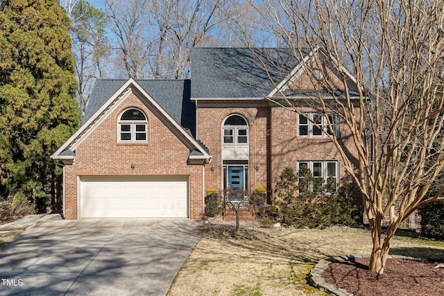 traditional-style house featuring a shingled roof, concrete driveway, brick siding, and a garage