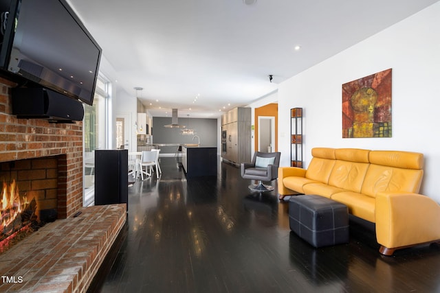 living area featuring recessed lighting, a brick fireplace, and dark wood-style flooring