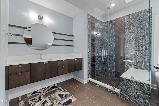 full bath featuring a stall shower, baseboards, wood finish floors, and vanity