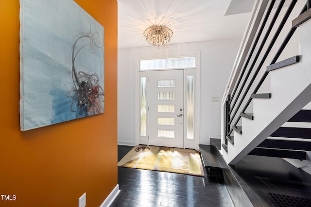 entrance foyer with baseboards, stairway, dark wood finished floors, and a chandelier