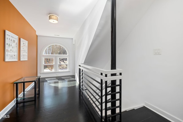 hallway featuring dark wood-type flooring and baseboards