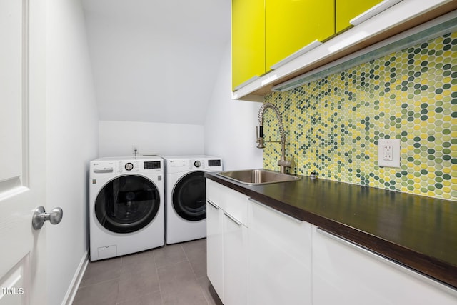 laundry room featuring light tile patterned flooring, a sink, baseboards, cabinet space, and washing machine and clothes dryer