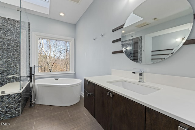 bathroom with a stall shower, a soaking tub, vanity, wood finish floors, and recessed lighting